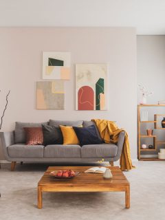 wooden coffee table and yellow chair in front of grey couch with pillows in trendy living room, What Color Accent Wall Goes With Beige?