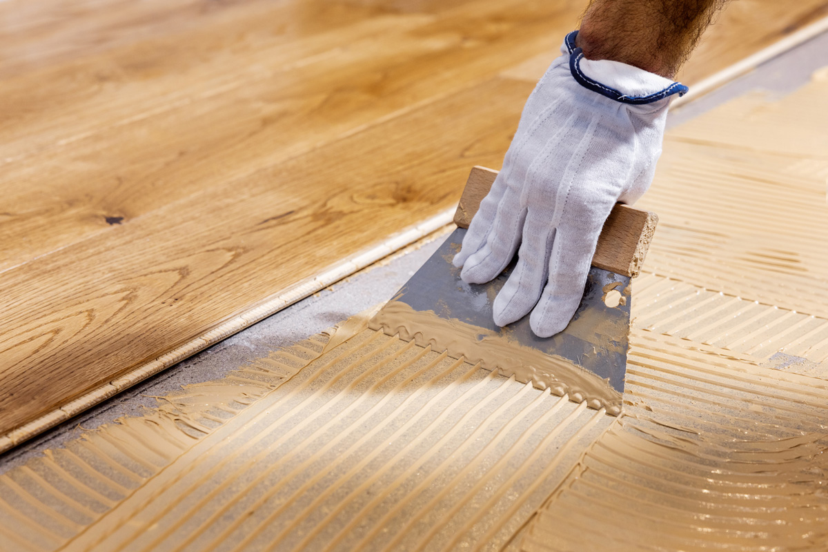 worker apply adhesive for 3 layer parquet flooring