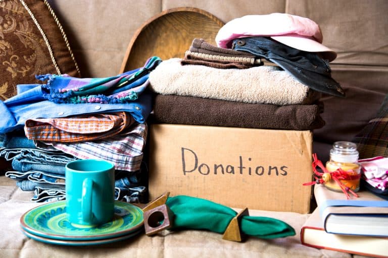 A box filled with cloths and other used goods for donation, Goodwill Vs. Savers Vs. Salvation Army: Where To Donate?
