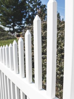 A closeup angled view of a white picket fence, as a background, leading into the horizon.