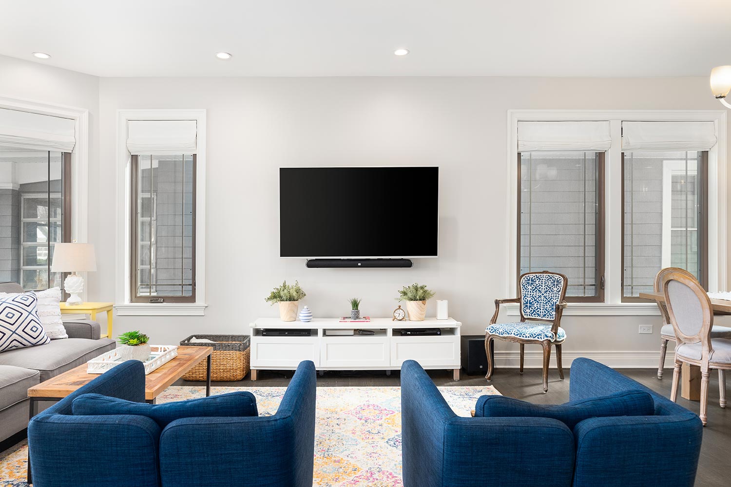 A cozy living room with blue chairs sitting in front of a mounted television