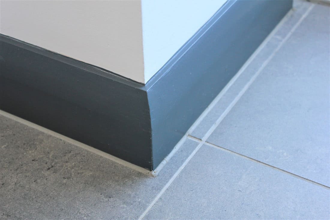 A gray colored baseboard inside a white living room matched with gray tiles