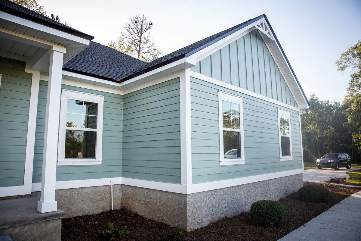 A house wooden siding painted in a turquoise color with white painted trims and black asphalt shingle roofing