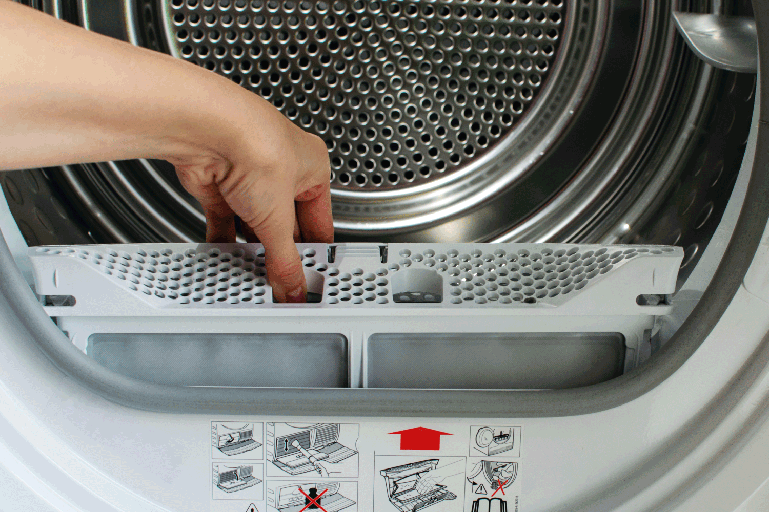 A housewife holds a lint trap from a front-loading tumble dryer. Woman's hand