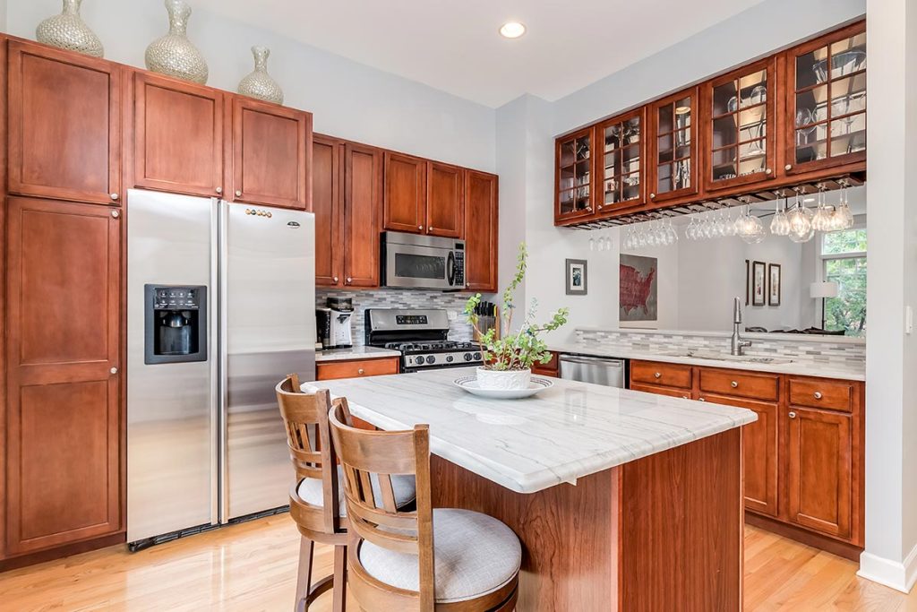 A kitchen with maple wood cabinets, a white granite counter top, and stainless steel GE appliances