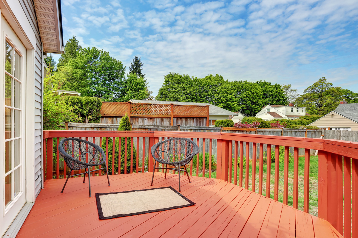 Backyard of craftsman home with red deck.
