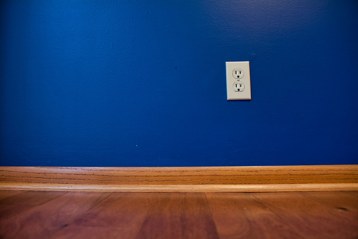 Blue Wall with Wood Flooring and an Electrical Outlet