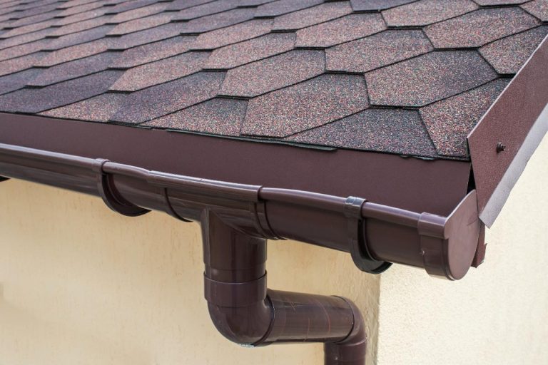 A brown plastic drainage on the roof near the shingles, What Color To Paint Gutter And Downspouts? [8 Options]