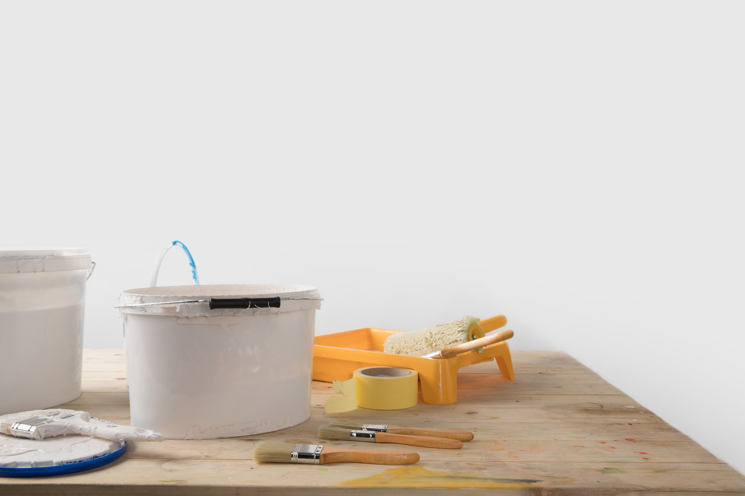 Buckets with paints and plastic tray on wooden table — Free Stock Image