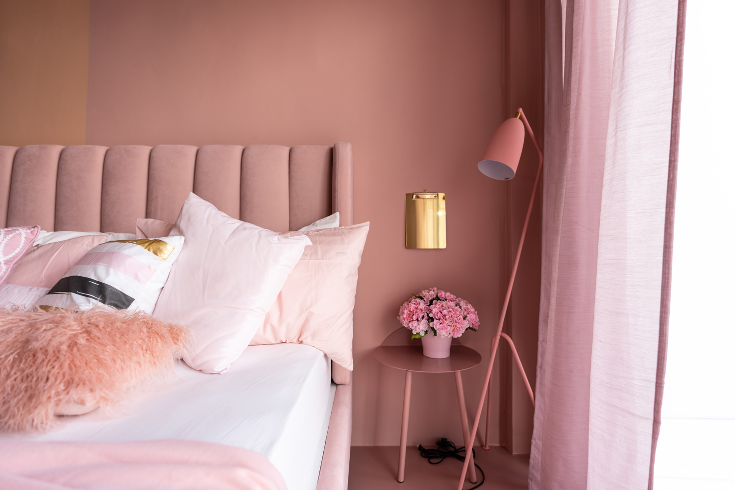Cozy Pink Bedroom corner with baby pink velvet fabric bed decorated by blanket, pillows and pink floor lamp with two-tone pink painted wall on the background interior bedroom furniture concept