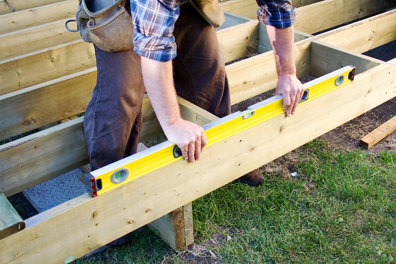 Carpenter checking level of deck boards
