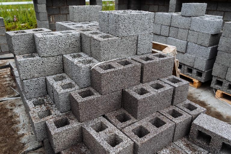Cinder blocks of gray concrete are neatly stacked in a pile, How Much Does A Cinder Block Weigh?