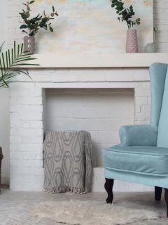 A classical living room with blue armchair and a fireplace, 4 Best White Paints For Brick Fireplace