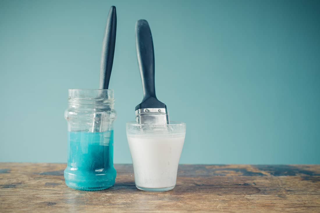 Cleaning small paint brushes on cup filled with paint thinner
