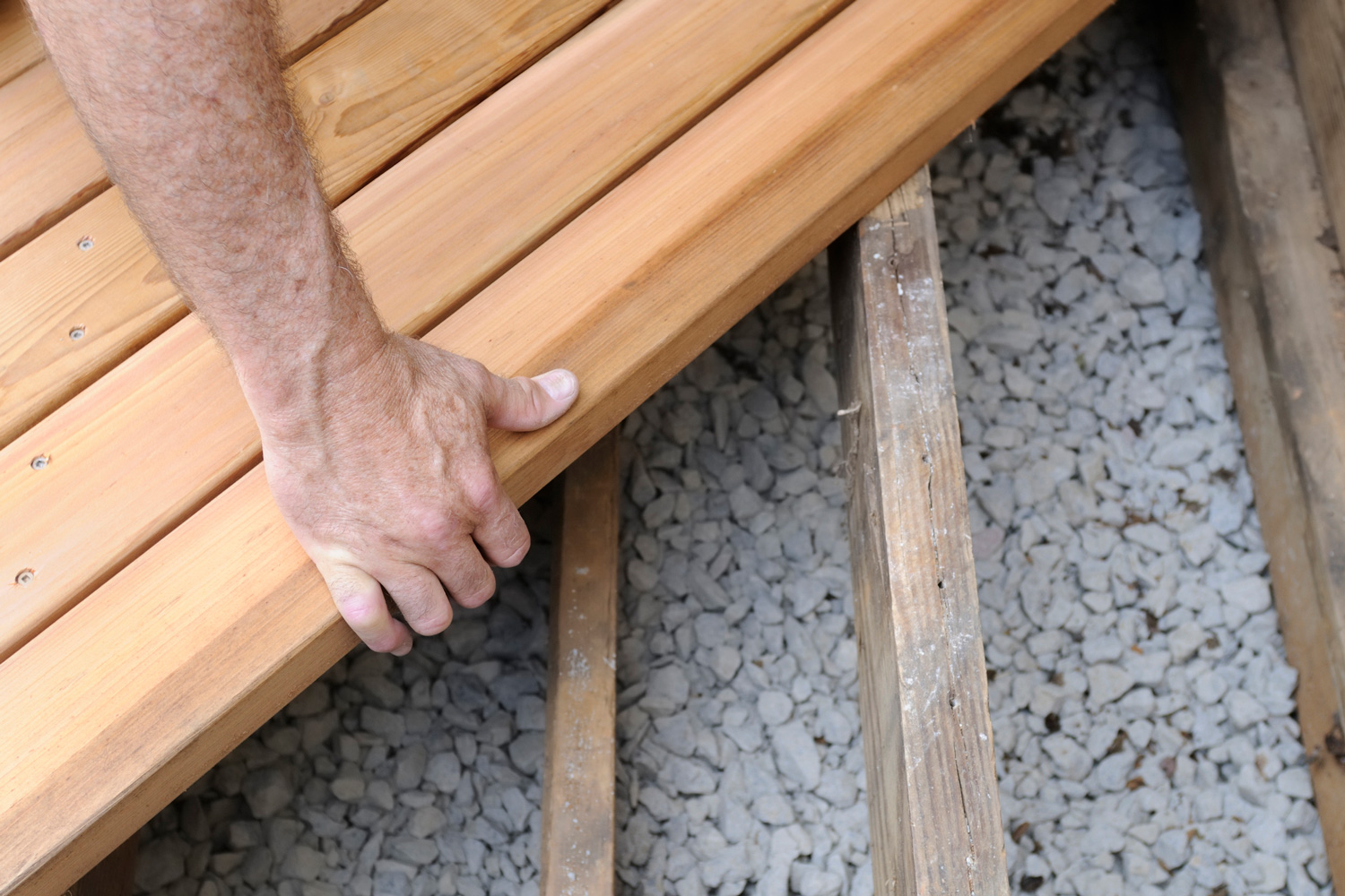 Close-up of worker putting new cedar boards on deck