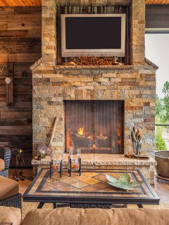 Covered Outdoor Patio Outside New Home with Couch Chairs TV Fireplace and Roaring Fire, How To Update A Stone Fireplace [8 Awesome Ideas]