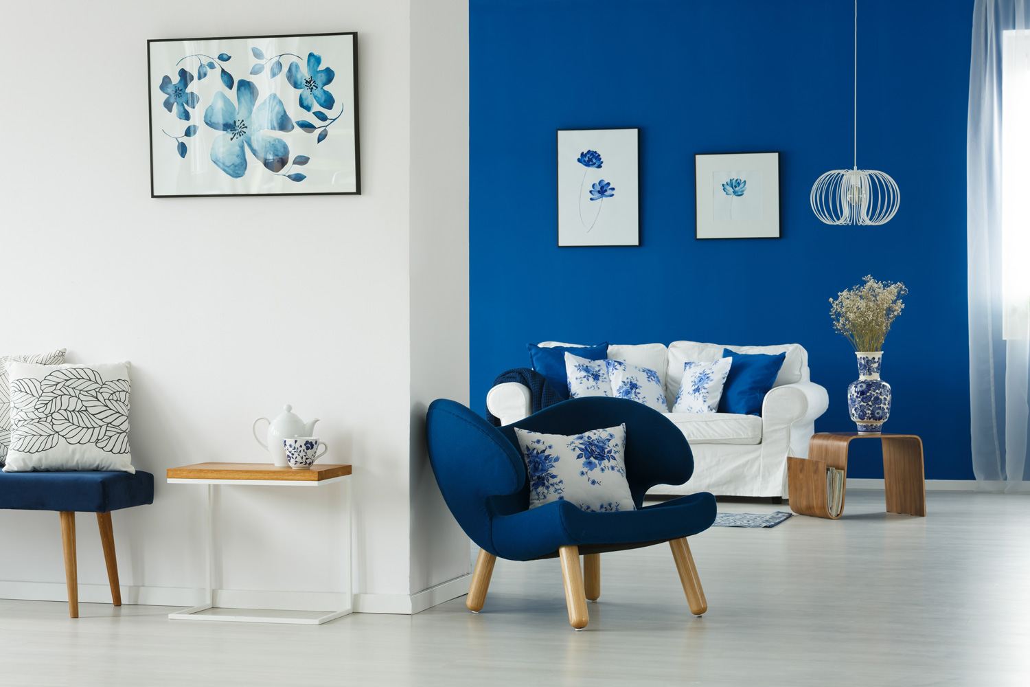 Cozy blue and white living room with flowery patterns on pillows and posters