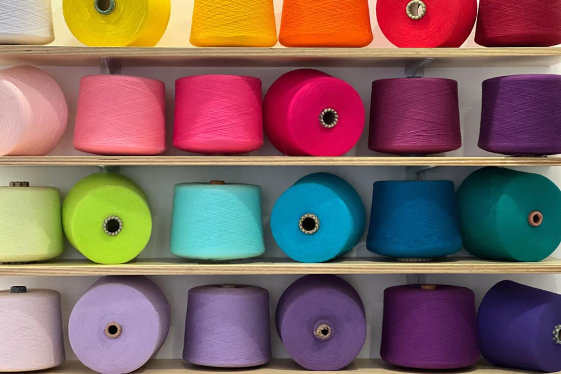 Different colors of yarn spools at a shelf