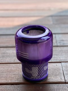 Dyson cordless vacuum HEPA filter head on a wooden floor, How To Clean A Dyson Filter [Steps Explained]
