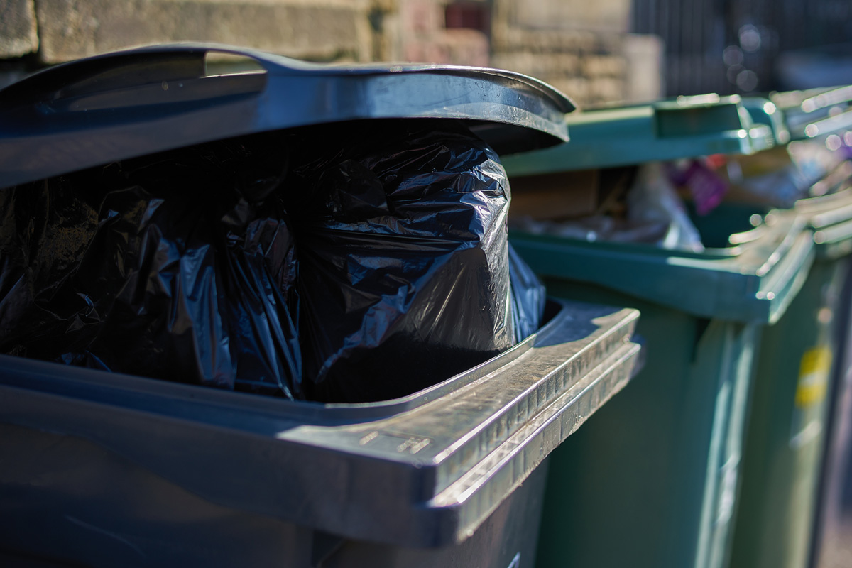 Gray and green garbage cans overfilled with domestic refuse
