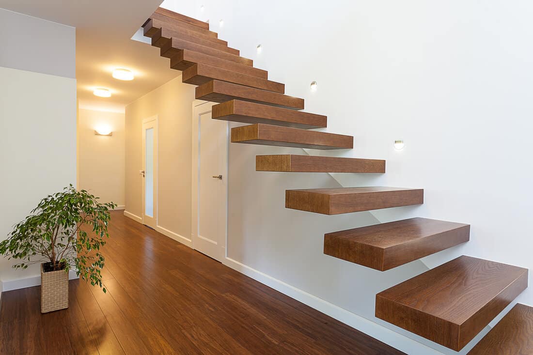 Hardwood staircase and white painted walls with lights on the walls