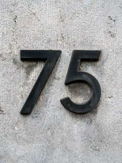 House number 75 mounted on a gray wall, How Much Space Between House Numbers Should You Have?