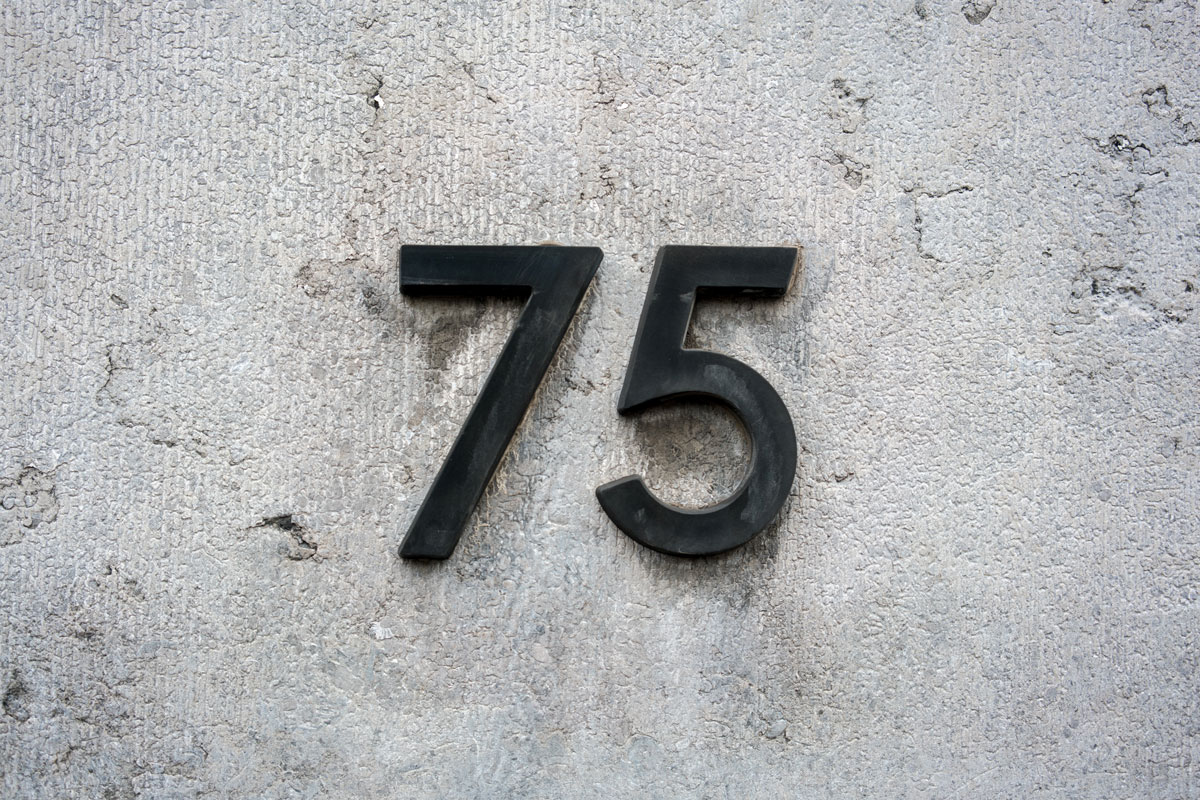 House number 75 mounted on a gray wall
