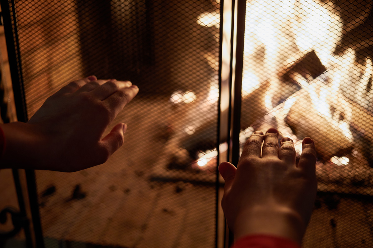 Human hands warming at fireplace.