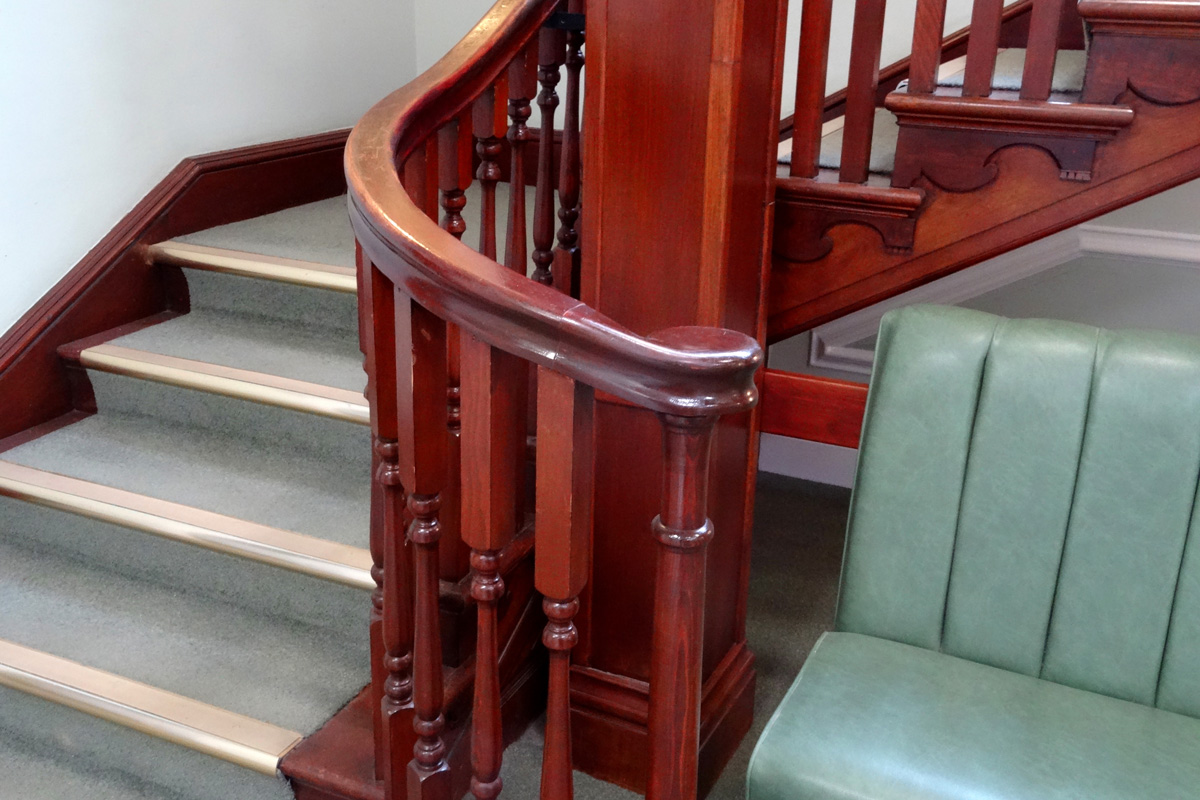 Image of wooden stair bannisters / spindles, staircase, green-carpet, metal-nosing