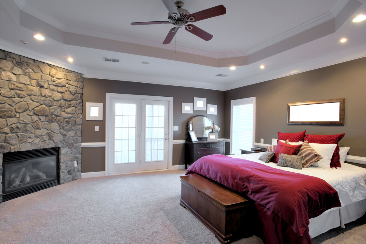 Interior of a large modern bedroom with a fireplace and ceiling fan