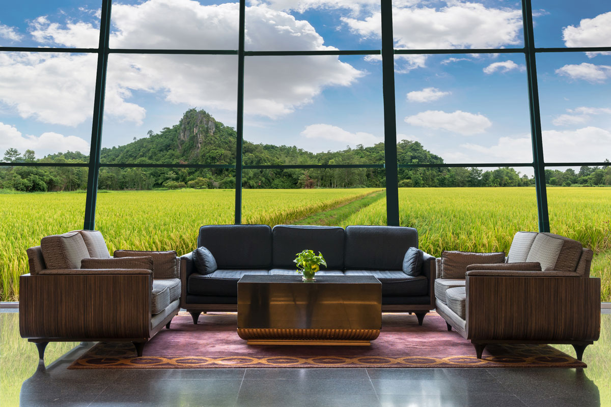 Interior of an entertainment room with leather sofas and a scenic view of a rice field and a huge mountain