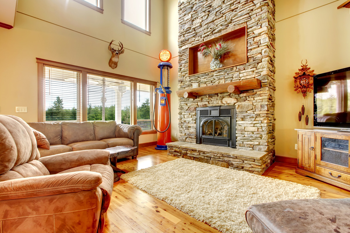 Living room with high ceiling, stone fireplace and leather sofa.