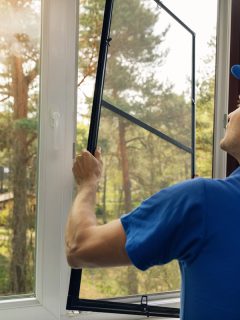 Man cleaning window of a home and removing a screen, How To Remove Screen From Window [Even Without Tabs]