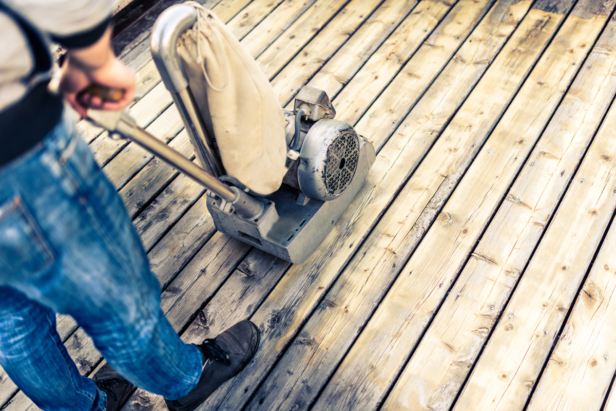Man rented a sanding machine to prepare the backyard deck for painting