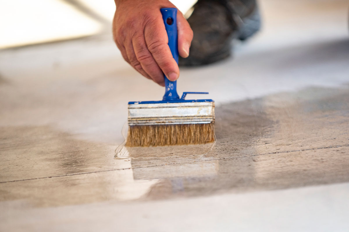 Manual worker painting concrete floor for protection