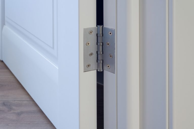 Metal chrome hinged hinges on a white interior door - How To Keep A Door From Closing On Its Own