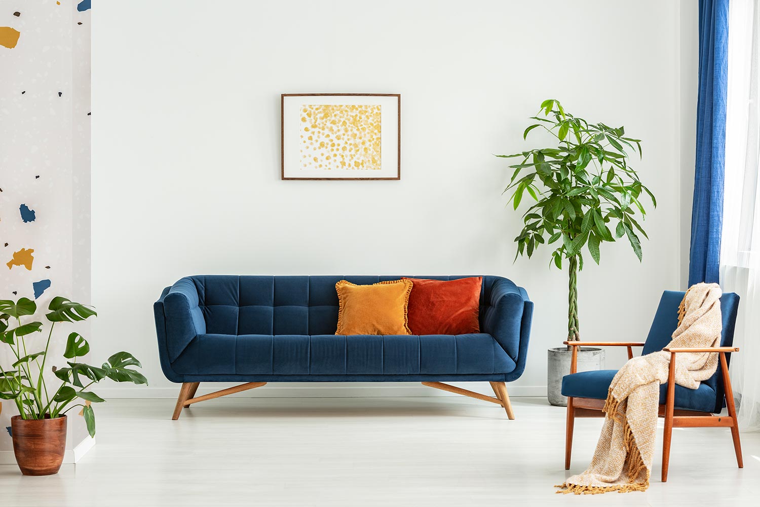 Mid-century modern chair with a blanket and a large sofa with colorful cushions in a spacious living room inter