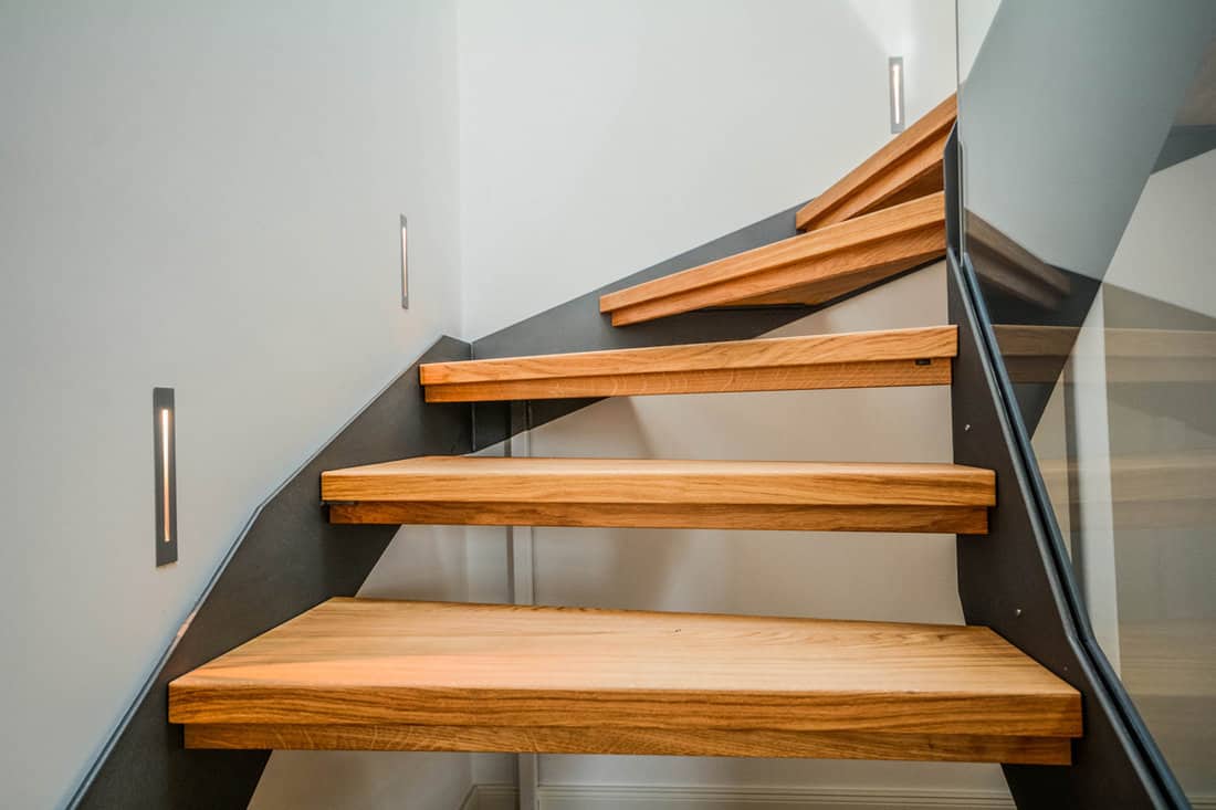 Minimalist stairs with wooden steps and metal brackets and guide lights on the side