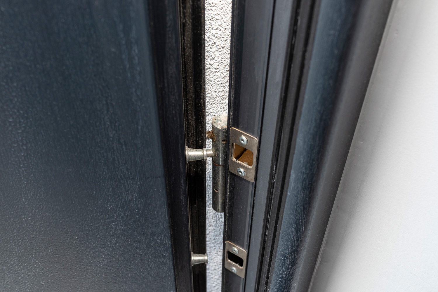 Modern anti burglary entrance door with visible hinges and bolt, in anthracite color.