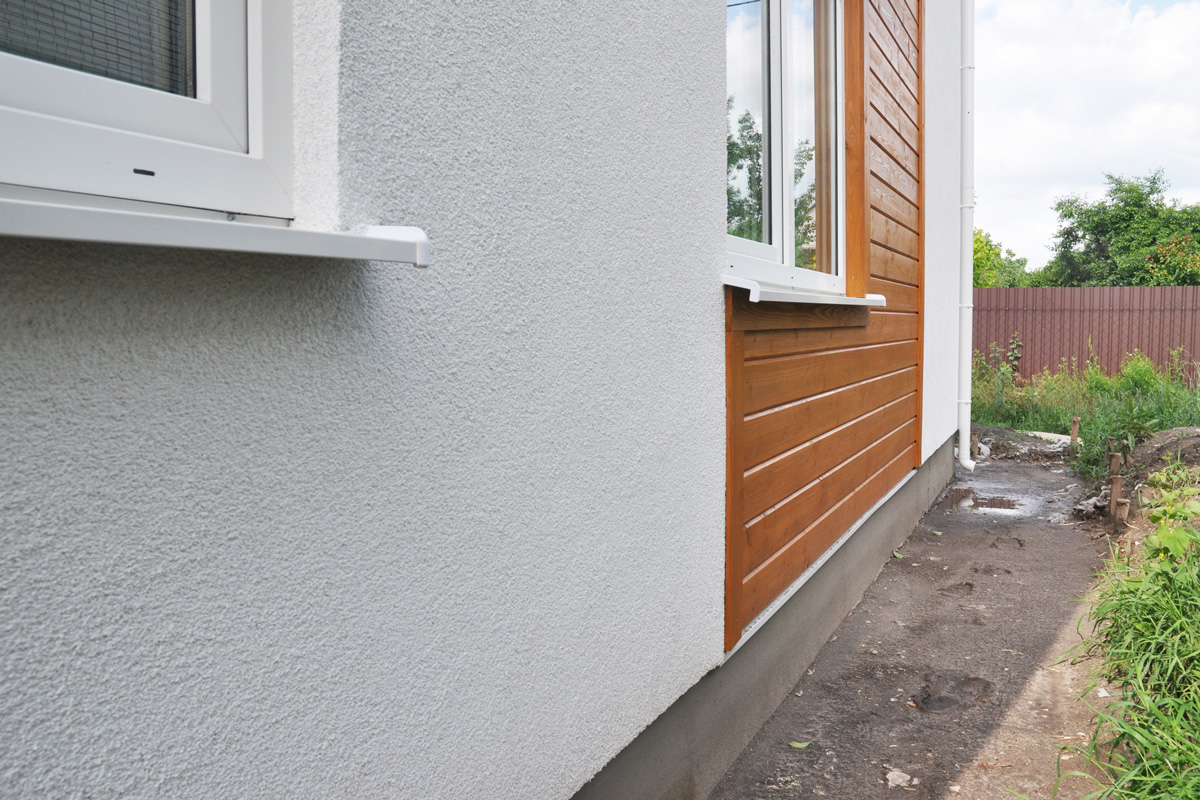 Modern house facade insulation under plastering, stucco and wood wall siding.