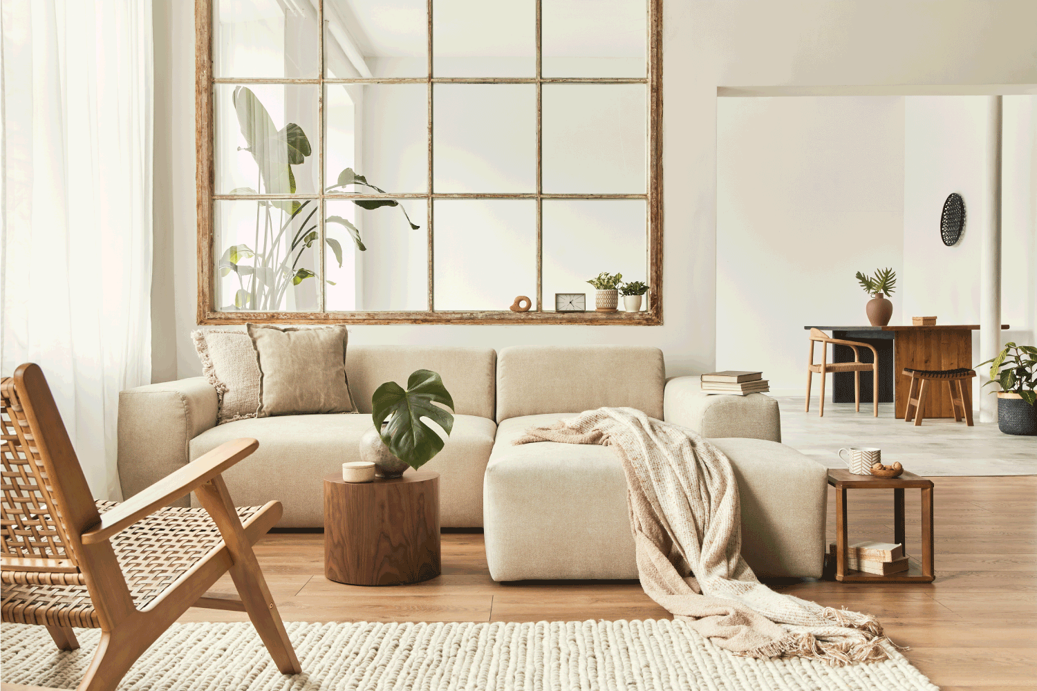 Modern interior of open space with design modular sofa, furniture, wooden coffee tables, plaid, pillows, tropical plants