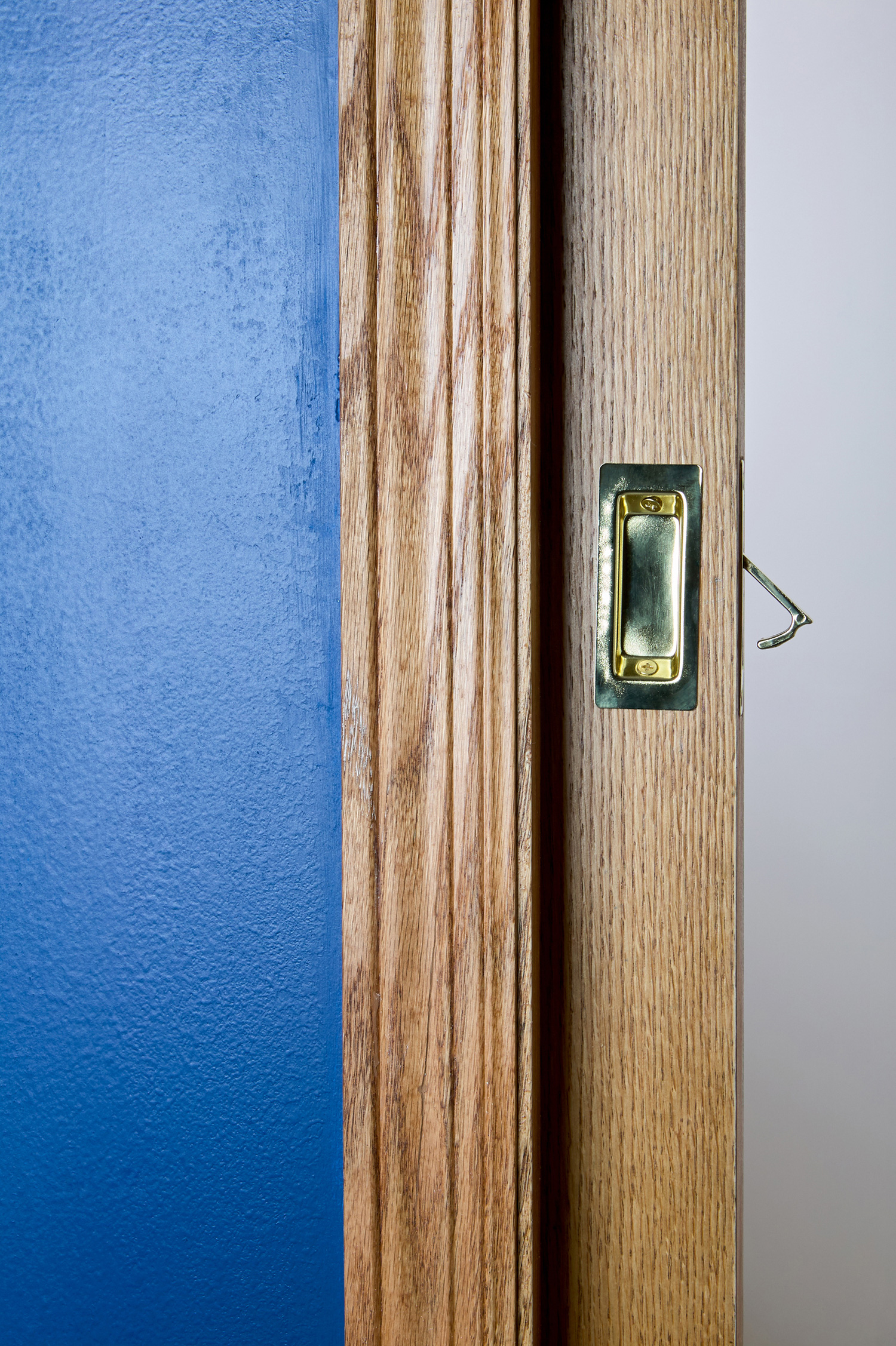 Open sliding wooden pocket door concealed with a wall cavity inside a house with close up detail of the handle