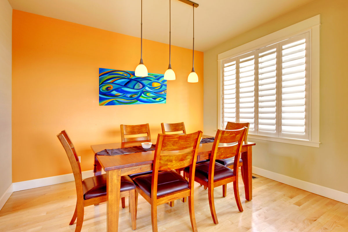 Orange dining room with wood table and hardwood floor