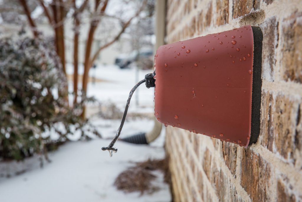 Outdoor faucet cover in the winter with icicles on it