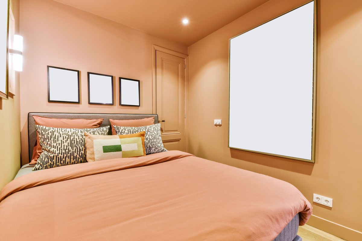 Peach bedroom with many paintings and a bed covered with a peach fluffy bedspread