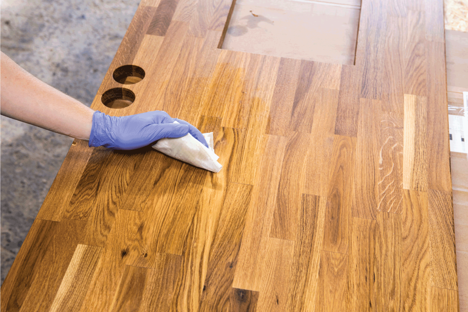 Person working, rubbing oiling with linseed oil natural wooden kitchen countertop before using