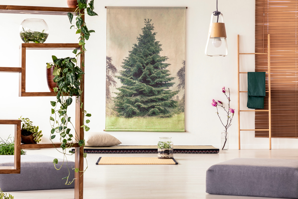 Plants on a wooden shelf in an oriental living room interior with a tatami, mat, poufs, ladder and tree poster