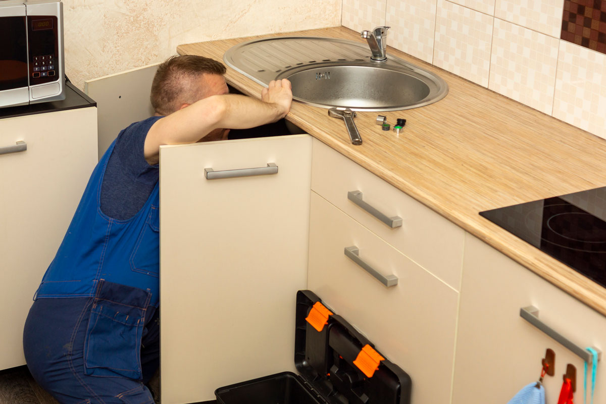 Plumber installs a sink with a faucet to water pipe in kitchen