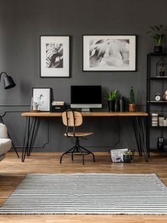 Posters on grey wall above wooden desk with computer monitor in modern workspace interior with plants, Do Gray And Beige Go Together [Inc. 11 Rooms That Show They Can!]