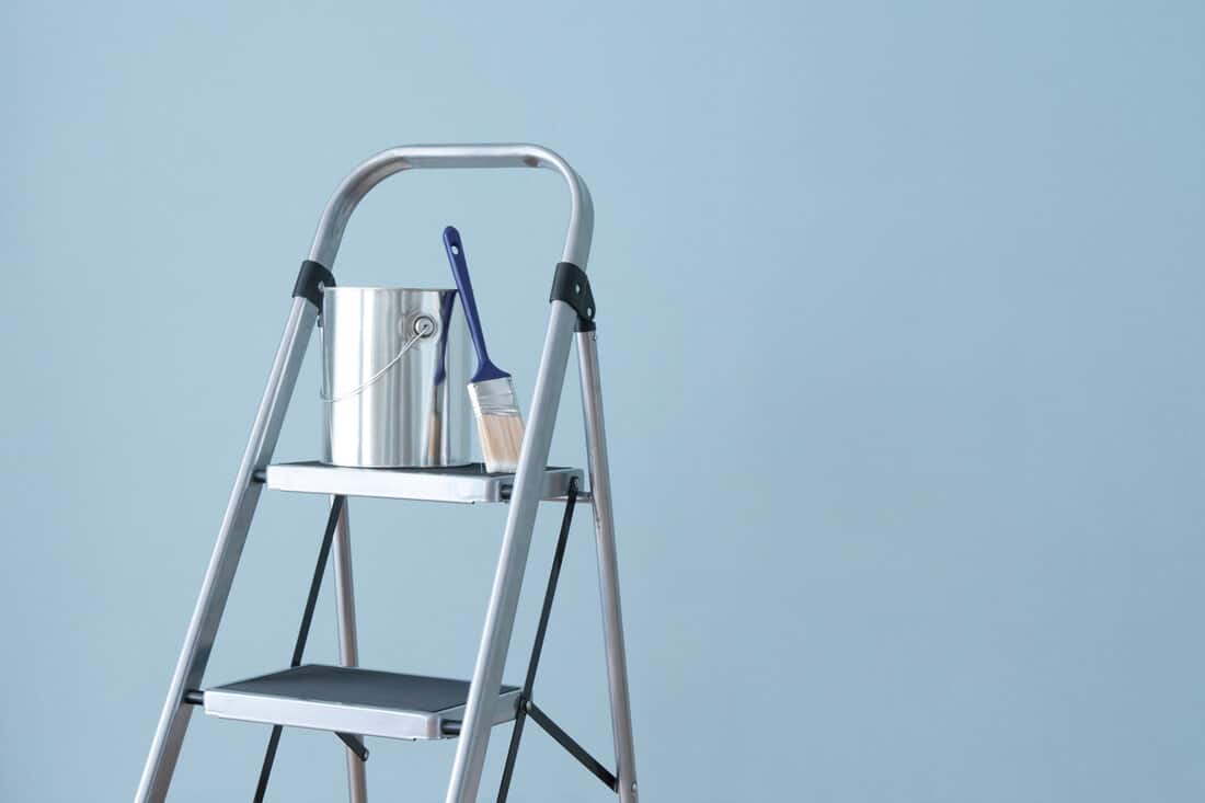Preparing to paint the wall. Painting tools on a metal ladder.